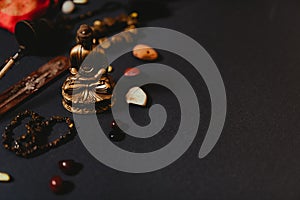 Occult symbols laid out on a black background. Aroma stick, Buddha figurine, stone rosary.