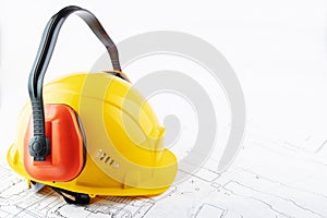 Occupational Safety and Health, ear protectors construction hard hat on background of architectural drawings with copy space,