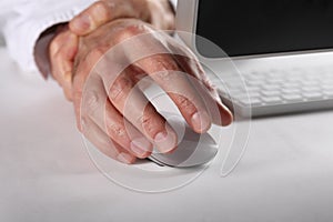 Occupational tendinitis disease concept: man working at computer massages his right fist photo