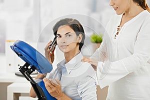 Occupied businesswoman getting massage photo