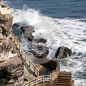 The Ocean against the rocks of the cliff at day time, wave splash and sea foam