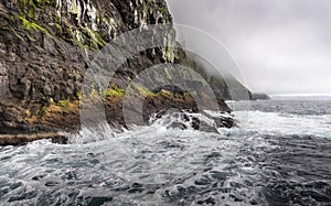 Ocean ahead of a rocky mountain beneath the gloomy clouds