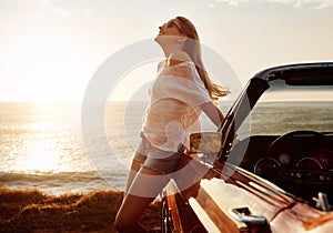 Ocean air and wind in your hair. a happy young woman enjoying a summers road trip.