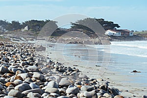 Ocean beach with large stones and sand under a blue sky and clouds