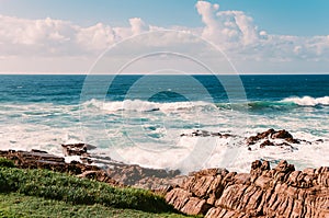 Ocean beach in Margate, SA, blue sky, white clouds, turquoise waves, rocks