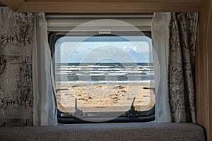 Ocean beach Sea view from the window of a camping caravan camper trailer. Road trip on the coast of sweden