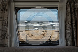 Ocean beach Sea view from the window of a camping caravan camper trailer. Road trip on the coast of sweden