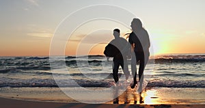 Ocean beach, sunset and silhouette of couple running, having fun and bonding on tropical adventure journey. Water, sea