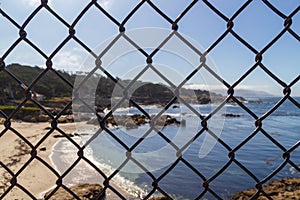 Ocean behind metal mesh fence . Restraint of liberty