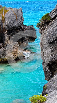 Ocean Blue Waters with black Rocky Beach Blue Sky white clouds in the horizon