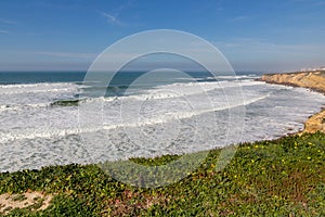 Ocean coast with grass, moviment waves with foam. photo