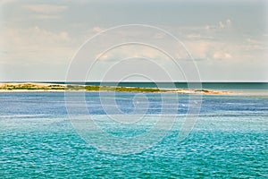 Ocean coast with turquoise water and white clouds sunny blue sky.