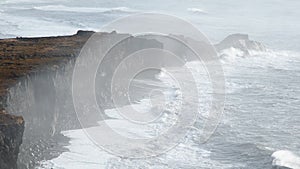 Ocean coastline in Iceland. Volcanic mountains, black cliffs and huge waves. Famous tourist attraction in Iceland