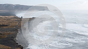 Ocean coastline in Iceland. Volcanic mountains, black cliffs and huge waves. Famous tourist attraction in Iceland