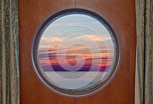 Ocean and evening sky sunset seen through the porthole of a ship