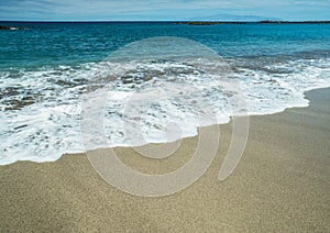 Ocean foam covering beautiful long sandy beach