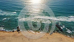 Ocean foamy waves approaching sandy shore. Top view