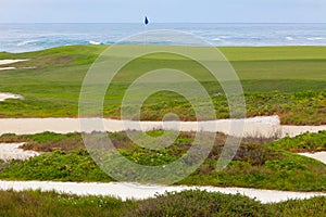Ocean front golf course, sand bunkers and greens leading to hole