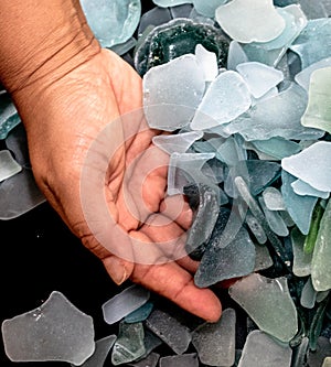 Ocean glass patterns on backgrounds with hands holding and grabbing, blues, whites, brown, green. Crafts