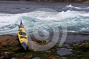 Ocean kayak beached on rocky shore at tidal rapids