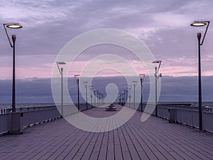 Ocean Pier at Dusk with Streetlights and Cloudy Sky photo