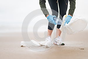 Ocean pollution. A volunteer collects used plastic bottles in a sack on the beach. Focusing on the foreground. Social and