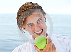 Ocean, portrait and happy woman eating apple for healthy food, diet and wellness in outdoor morning. Fruit, smile and