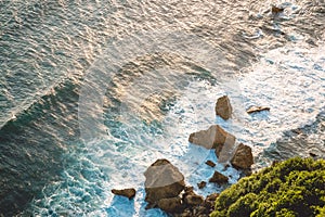 Ocean with rocks and cliff in Uluwatu, Bali at sunset light