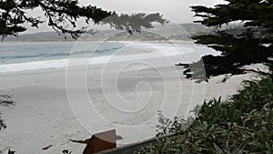 Ocean sandy beach, California coast, sea water waves crashing. Foggy weather.