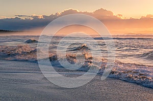 Ocean sandy beach with mild waves at sunrise