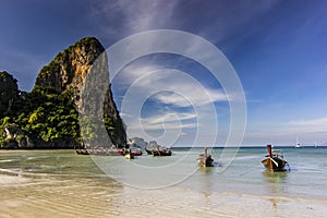 Ocean seashore with island and boat on water at sunset in Krabi, Thailand