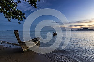 Ocean seashore with island and boat on water at sunset in Krabi, Thailand