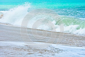 An ocean shorebreak in front view. Big beautiful green blue wave splashing with backwave and ready to break out. White foam