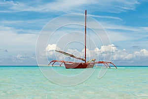 Ocean summer day view with blue sea and sky with white clouds and red boat