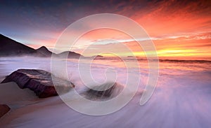 Ocean sunrise as large waves wash onto the beach