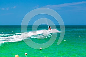 The ocean is turquoise and the boat water bike is far away with two people. Thailand. Samui. Gulf of Thailand. Lamai Beach