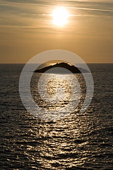 Ocean view with setting sun and sailboat on horizon