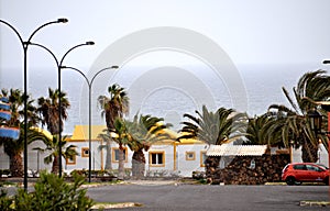 Ocean views, white bungalows with yellow roofs and many palm trees in Caleta de Fuste, Fuerteventura, Canary islands