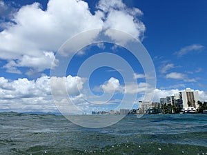 Ocean waters ripple off the coast of waikiki with hotels lining