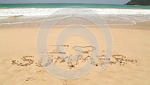 Ocean wave approaching words I love summer written in sand on beach