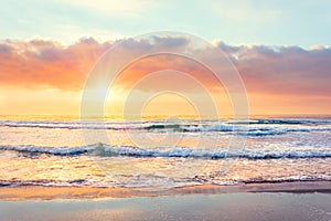 Ocean wave on the beach at sunset time, sun rays