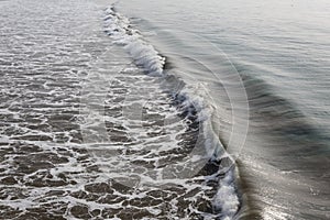 Ocean wave dividing calm sea and turbulent foamy water