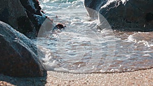 Ocean wave gushing through gap between rocks on the sea shore. Low angle