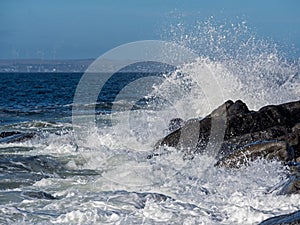Ocean wave smashes into rocks creating splash of water.