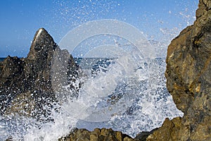 Ocean wave splashing over rocks closeup