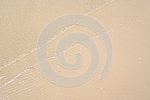 Ocean wave on tropical beach with golden sand