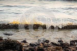 Ocean Waves against the rocks.Sea shock wave foam on the pebble stone beach