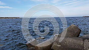 Ocean waves beat against the stone breakwaters in the port. View of the ocean and stone breakwaters on the shore.