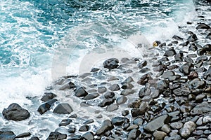 Ocean waves on black pebble stone coast