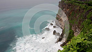 Ocean waves break against high coastal cliffs.